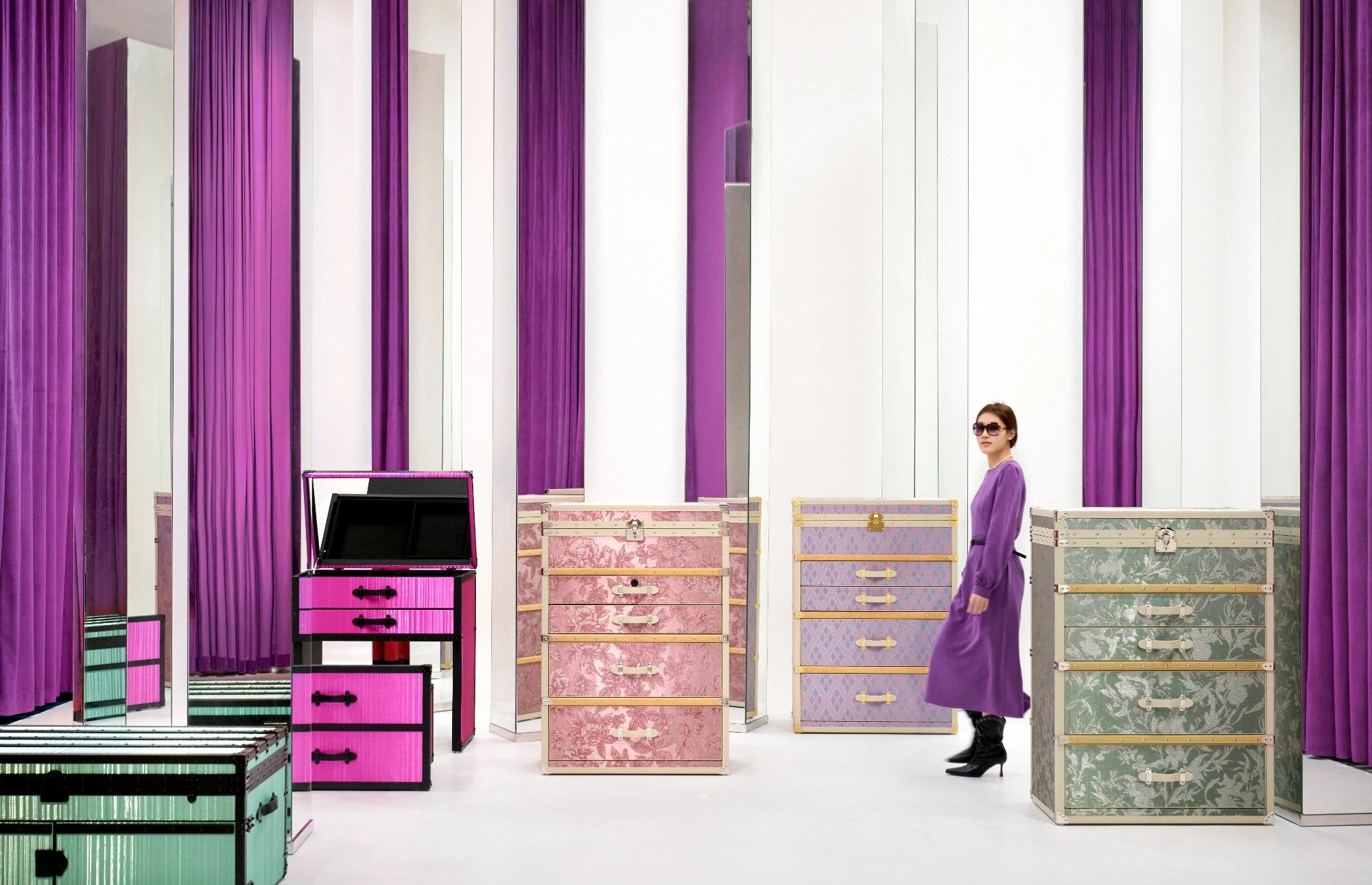 Woman standing among colorful storage drawers with purple curtains in the background